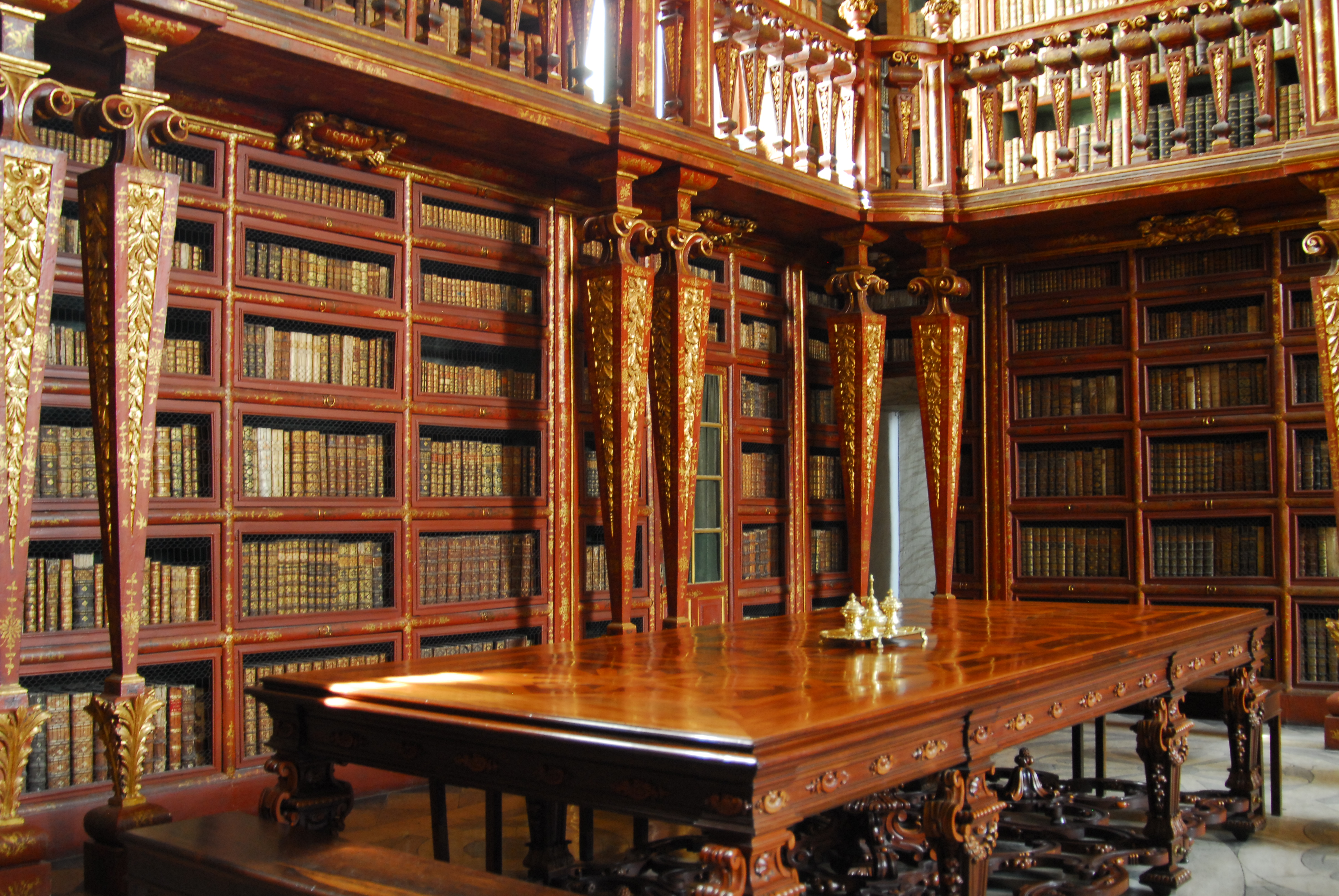 Interior da Biblioteca Joanina, com estantes de madeira e mesas de leitura