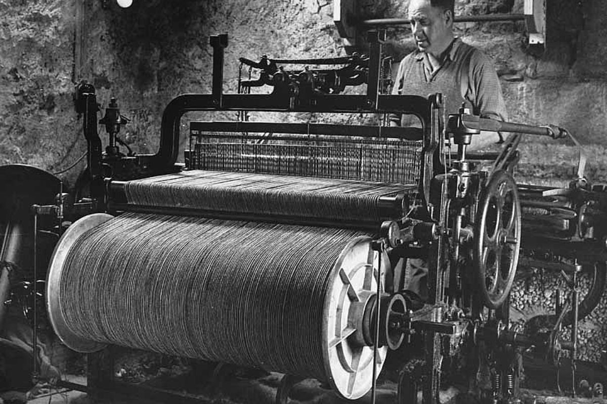 Tecelão de Harris Tweed trabalhando em tear manual em casa, nas Hébridas Exteriores, por volta de 1960